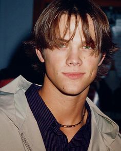 a close up of a person wearing a shirt and tie with his hair pulled back