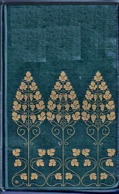 an old book with gold leaf designs on the front and back cover, sitting on a blue surface