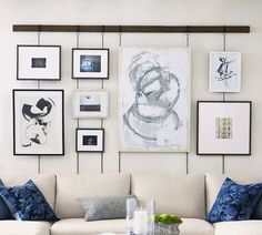 a living room filled with white couches and framed pictures on the wall above them