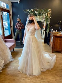 a woman in a wedding dress is taking a selfie with her cameraman behind her