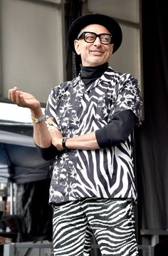 a man in zebra print clothes standing on stage with his hands folded out and smiling