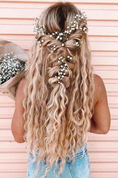 a woman with long curly hair and flowers in her hair is holding a paper bag