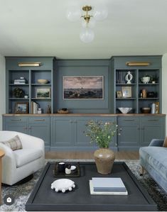 a living room with two couches and a coffee table in front of the bookshelves