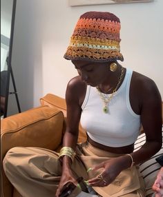 a woman sitting on top of a couch wearing a hat and holding a cell phone