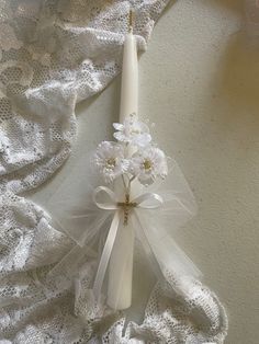 a white candle and some flowers on a lace doily next to a flower arrangement