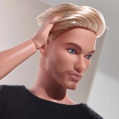 a male mannequin with blonde hair and blue eyes wearing a black sweater is shown in front of a white wall