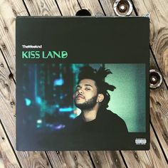 the album cover for the song kiss land is displayed on a wooden table next to eyeglasses