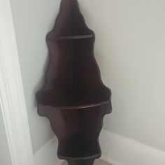 a corner shelf in the corner of a room with tile flooring and white walls