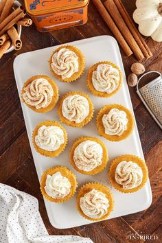 cupcakes with cinnamon butter frosting on a white plate next to cinnamon sticks