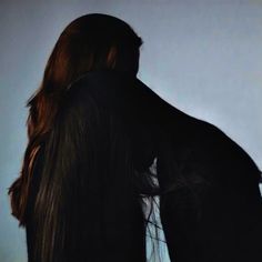 the back of a woman's head with long, straight hair in front of a white wall