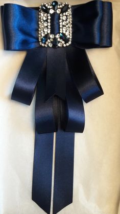 the sash is adorned with crystal brooches and blue satin ribbon, along with an embellished buckle