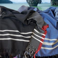 two scarves laying on top of each other next to the ocean