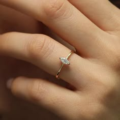 a woman's hand wearing a gold ring with a diamond on it and a white background