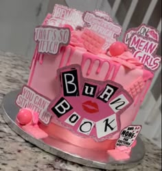 a pink cake decorated with the words burn book on it's side and lips