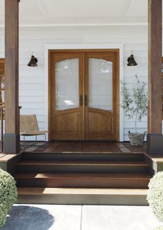 a front porch with two chairs and a wooden door