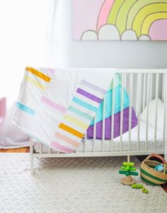 a white crib with colorful blankets and toys on the floor