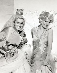 two women in dresses and tiaras posing for the camera with one woman wearing a veil