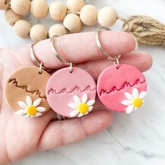 three handmade keychains with the word mama written in pink, white and yellow