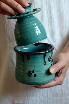 a person is holding a green pot with chocolate dripping from it and another hand holds the lid