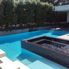 an empty swimming pool in the middle of a yard with trees and bushes behind it