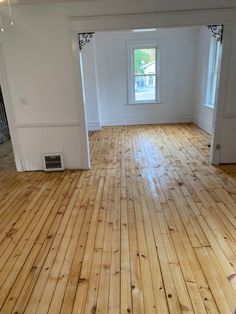 an empty room with hard wood floors and white walls