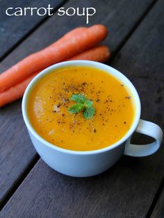 carrot soup in a white bowl next to two carrots on a wooden table with the words carrot soup written above it