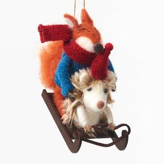 two stuffed animals are sitting on a sled ornament that is hanging from the ceiling