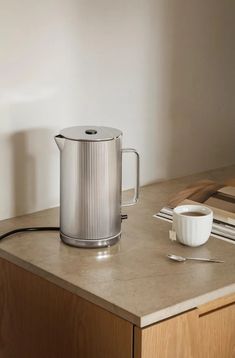 a coffee pot sitting on top of a counter next to a cup and saucer