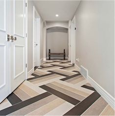 an empty hallway with white doors and black and beige floor tiles on the floor, along with a bench in the corner