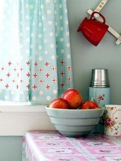 a bowl of apples sits on a table next to a cup and utensils