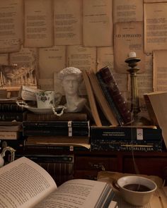 an old desk with books and a busturine on it, next to a cup of coffee