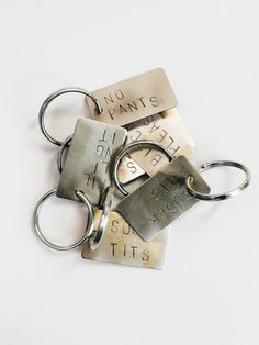 three metal key chains with no pants written on one side and two different sized tags attached to the other