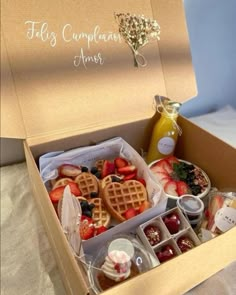 a box filled with lots of different types of food next to a bottle of juice