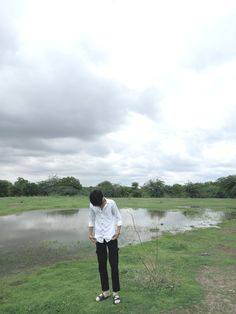 a man standing in front of a body of water with his head down on the ground