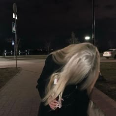 a woman with blonde hair walking down a sidewalk