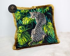 a pillow with a leopard on the front and green leaves on the back, sitting on a white furnishing