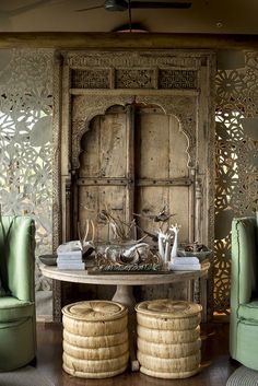 a room with green chairs and a table in front of an ornate wallpapered door