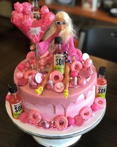 a barbie doll sitting on top of a pink cake covered in doughnuts and toppings