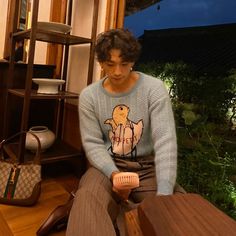 a young man sitting on top of a wooden bench next to a handbag and purse