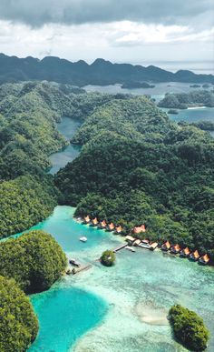 an aerial view of the water and land in front of some mountains with houses on them