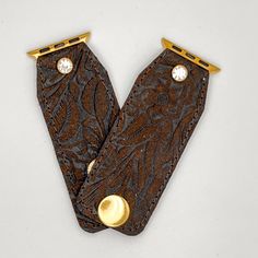 "Tyler" is our classic western girl! Beautifully hand-crafted watchband made with dark chocolate brown western tooled leather. The band is secured with gold fitting connectors that will slide into your apple watch securely. There are two gold high-quality snaps have been added to allow for adjustability and comfort fit. Each band is approximately 3.5 inches with snaps at .5 and 1.25. The secure clear crystal adds a nice little bling to the band! Fits the apple watch (38/40 mm band). All our piec Tooled Apple Watch Band, Tooled Leather Apple Watch Bands, Girl Beautifully, Designer Beanies, Band Fits, Western Girl, Dark Chocolate Brown, Key Design, Custom Watch