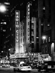 the radio city sign lit up at night in new york city, ny with cars passing by