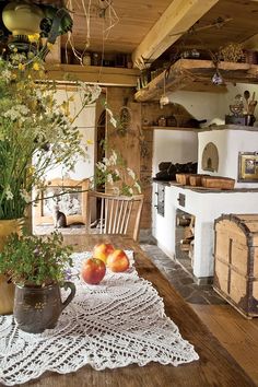 an old fashioned kitchen with apples on the table and potted plants in the center