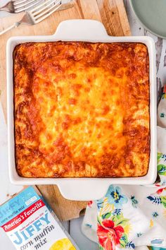 a square casserole dish with cheese on top next to a box of milk