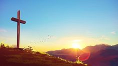 a cross on top of a hill at sunset