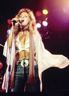 a woman standing in front of a microphone on stage