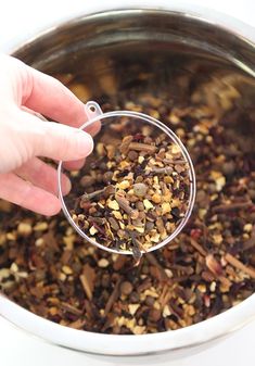 a person is scooping some food out of a metal bowl with a measuring spoon