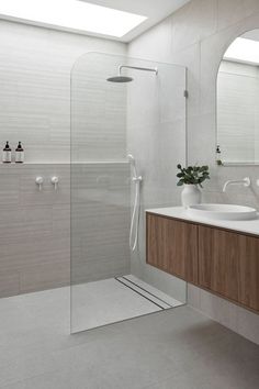 a white bathroom with two sinks and a shower in the corner, along with a large mirror on the wall