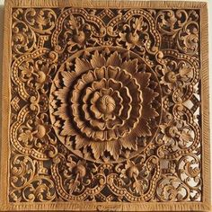 an intricately carved wooden panel with flowers and leaves on the center, is mounted on a wall