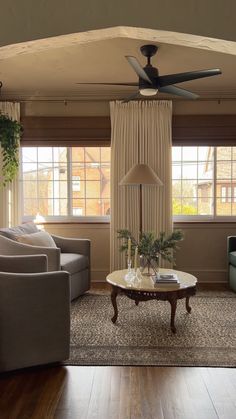 a living room with two couches and a ceiling fan in the middle of it